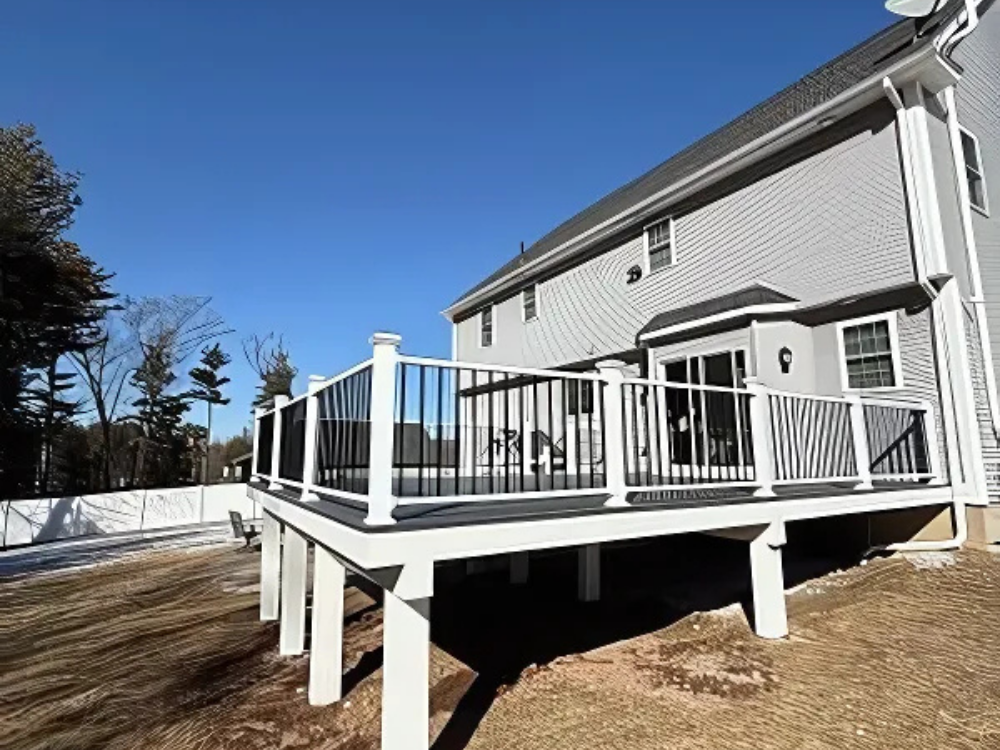 Custom Deck Construction showcasing an elevated white deck with black railings attached to a modern home.