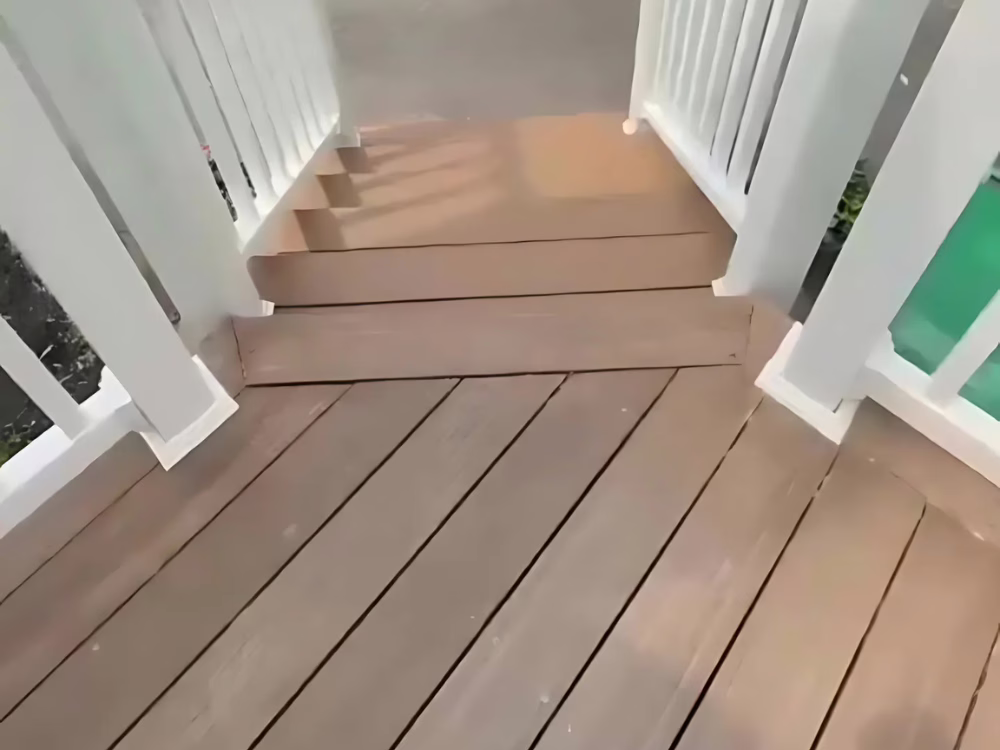 Deck construction in progress in Burlington MA showing close-up of newly installed composite wood and white railing.